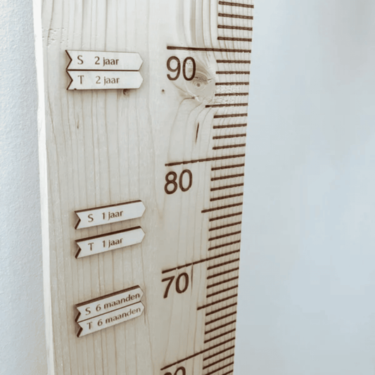 Houten pijltjes met op een houten groeimeter bevestigd. Zo is te zien oe groot je kind is geweest op welke leeftijd