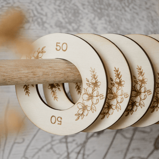 Houten kastverdeler op kledingroede voor baby- en kinderkleding, maat 50 t/m 98, met bloemen motief voor een georganiseerde kledingkast in detail.